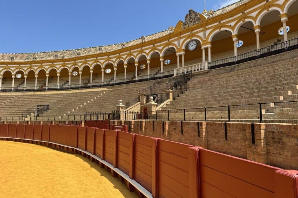 Interior of the Plaza de Toros de la Maestranza in Seville, showing the sand arena and traditional arches