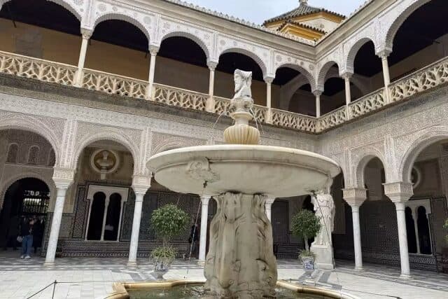 Main courtyard of Casa de Pilatos in Seville, featuring marble arches, Mudejar tiles, and a central fountain