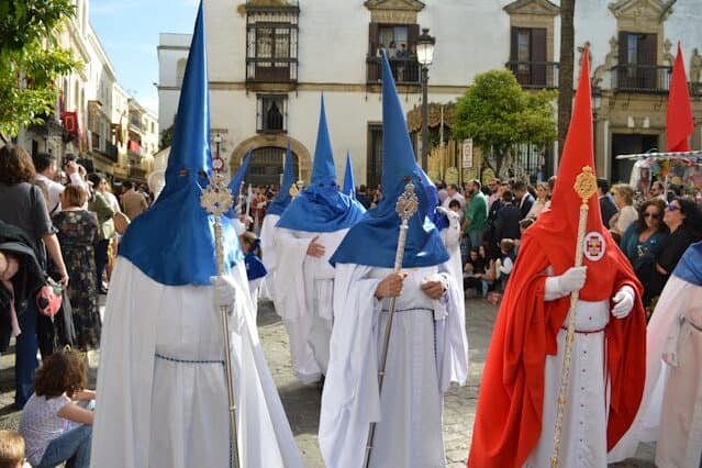 Nazarenos wearing red and blue capirotes during Semana Santa procession in Seville